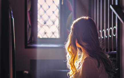 Jeune adolescente regardant par la vitre d'une église. Jeune adolescente regardant par la vitre d'une église. / © iStock